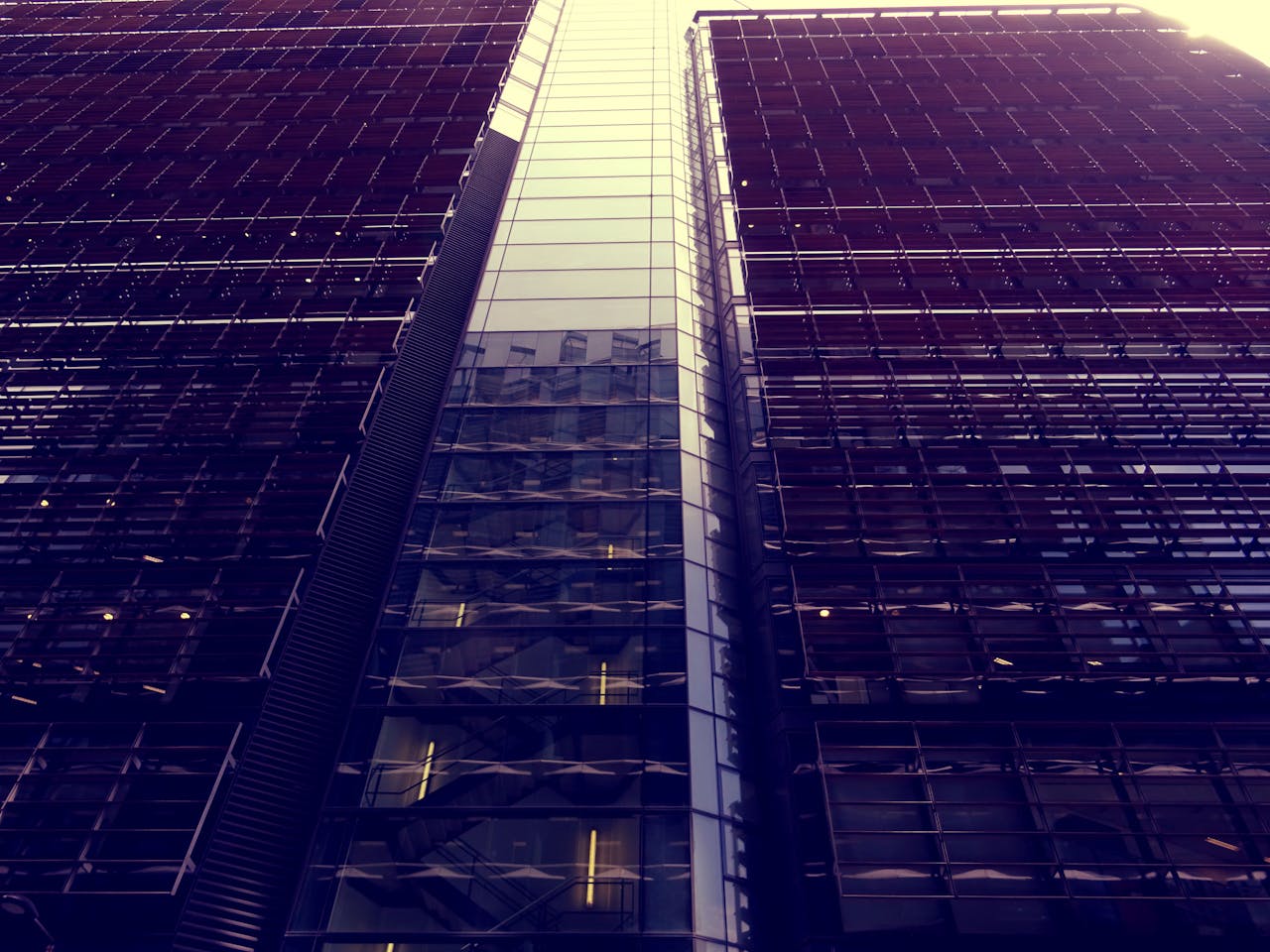 Low angle view of a modern skyscraper with reflective glass facade and urban architecture.